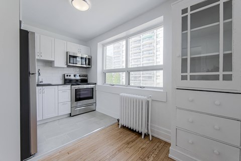 a kitchen with white cabinets and a large window